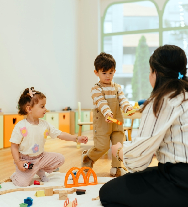 Kinderbegeleider speelt met peuters op speelmat