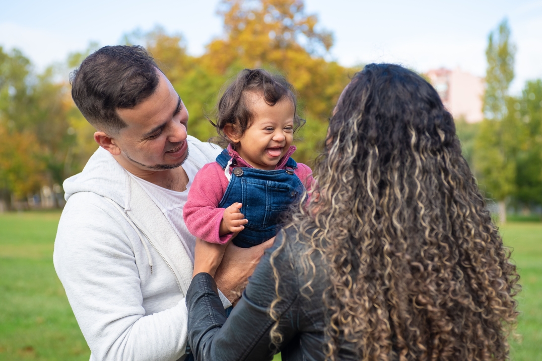 Blije ouders knuffelen hun kindje met een beperking