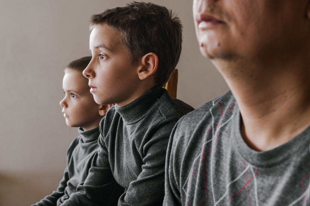 Jonge kinderen staren voor zich uit, ouder zit naast hen